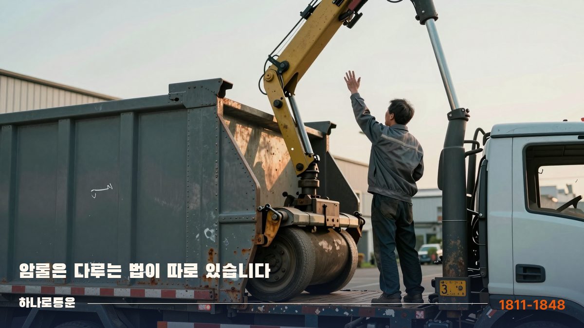 공장 앞에서 유압 암으로 컨테이너를 끌어 올리는 암롤 작업
